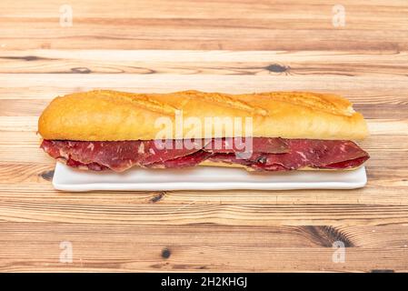 Great Spanish sandwich of smoked beef jerky sausage on white plate Stock Photo