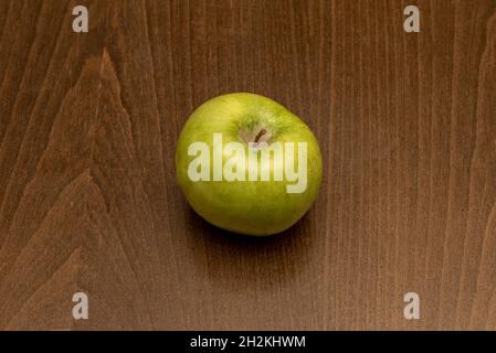lonely green apple on a dark colored wooden table Stock Photo