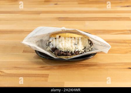 Venezuelan arepa domino of corn dough stuffed with black bean stew with grated fresh cheese Stock Photo