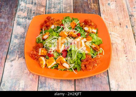 Salad of stewed peppers with lettuce, grated cheese and sliced breaded chicken fillets Stock Photo