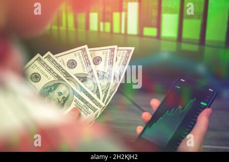 Businesswoman using smartphone with mobile phone investing application. Mobile stock market trading and crypto currency exchange concept background ph Stock Photo