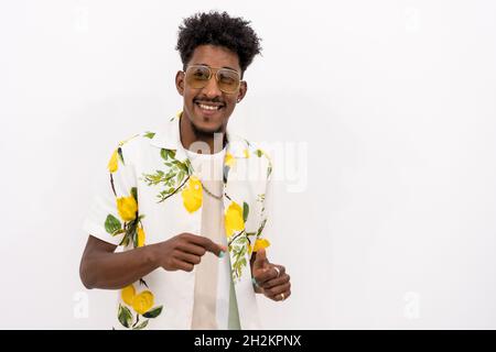 Young Cuban male in a floral shirt and black sunglasses moving and smiling on a white background Stock Photo