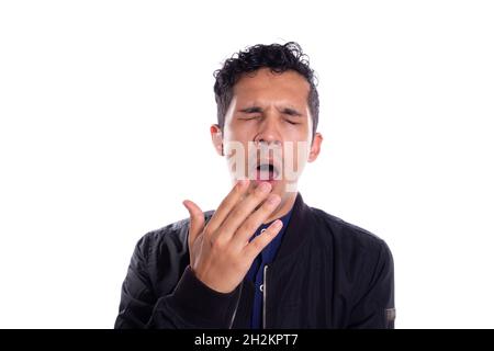 Young adult young man yawning, isolated on white background. Latin man yawning with hand near his mouth. Stock Photo
