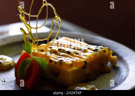 Sweet passion fruit pie with glazed sugar and strawberry decoration. Low key food dessert on plate concept Stock Photo