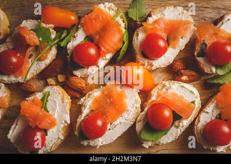 dry aged smoked salmon on the slices of bread and cream cheese sandwiches with cherry tomatoes and rocket salad Stock Photo