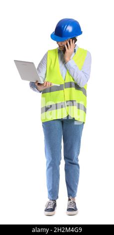 Female construction worker with laptop talking by mobile phone on white background Stock Photo