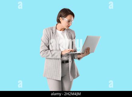 Female industrial engineer using laptop on blue background Stock Photo