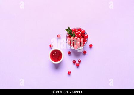 Bowls with lingonberry jam and berries on color background Stock Photo