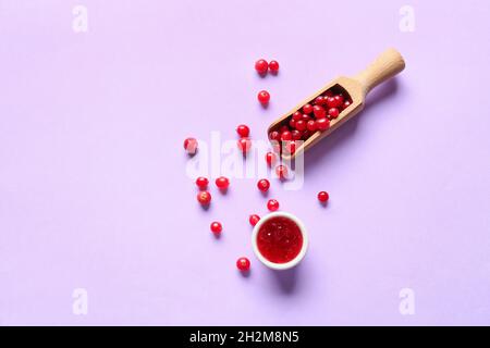 Bowl of tasty lingonberry jam and bowl with berries on color background Stock Photo
