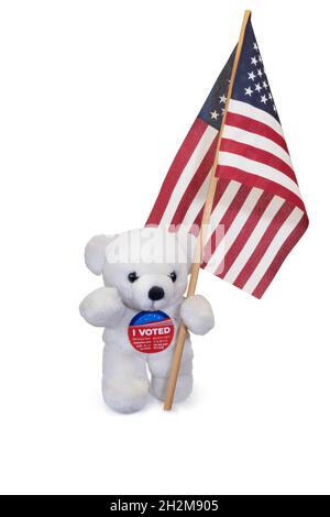 Cute teddy bear wearing I VOTED button and carrying American flag. Isolated on white background. Stock Photo