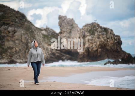 happy middle aged woman walking on beach Stock Photo