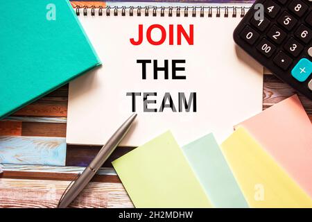 Text Join the team written on notepad, next to stickers, calculator and pen on wooden background Stock Photo