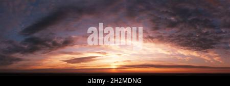Dramatic sky at sunset or sunrise. Dark mystical clouds. Bright sunlight in blurred orange clouds Stock Photo