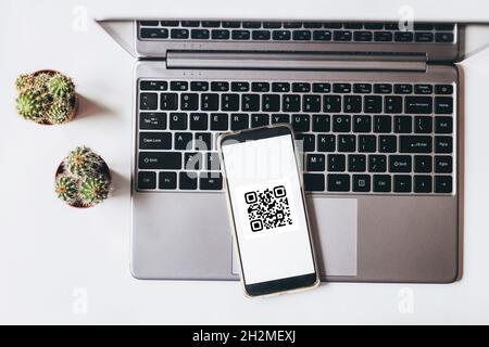 QR code scanning payment and online shopping concept. Mobile phone on the laptop. Stock Photo
