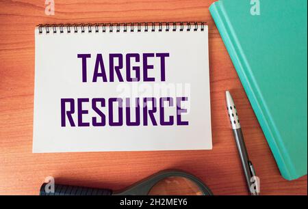Target resource - text in a notebook and a wooden table with a magnifying glass, diary and pen. Stock Photo