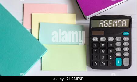 Calculator with agenda text on white background, plus colored notepads and stickers Stock Photo