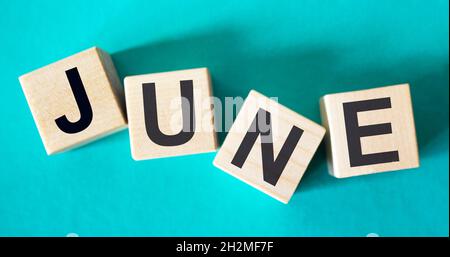Text June on wooden blocks and a turquoise background Stock Photo