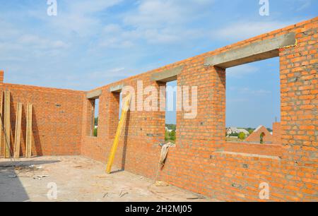 Interior of a Unfinished Red Brick House Walls under Construction without Roofing. Closeup on Attic Windows Hole Frame Construction Stock Photo