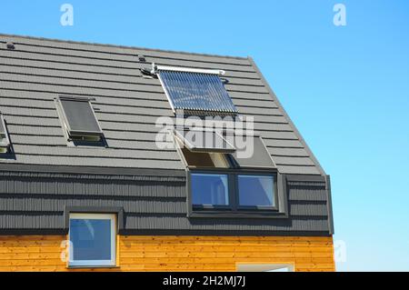 Closeup of Solar Water Panel Heating, Dormers, Solar Panels, Skylights, Ventilation and Air Conditioning Systems Installed on House Roof. Energy Effic Stock Photo