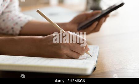 Female student writing in notebook, watching learning webinar Stock Photo