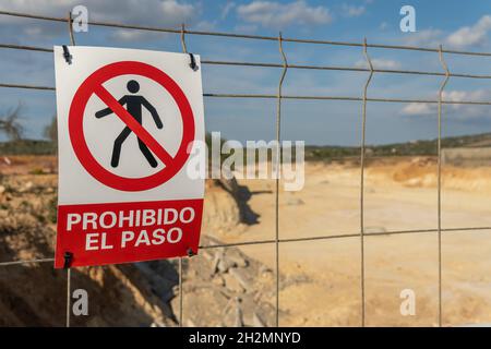 Close-up of a no trespassing sign, written in Spanish, next to a metal fence Stock Photo