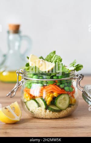 Glass jar with fresh raw vegetables and couscous groats. Healthy Meal Prep - recipe preparation photos. Healthy vegan dishes in glass containers. Weig Stock Photo