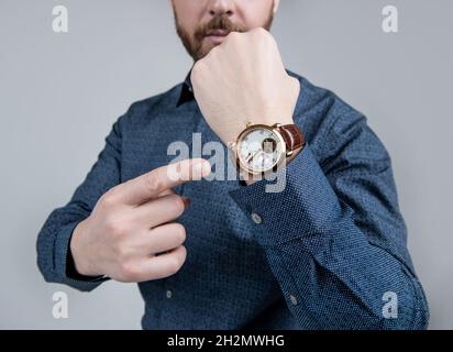 Man cropped view point finger at luxury wrist watch grey background, time Stock Photo