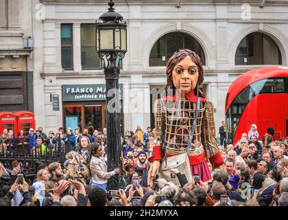 St Paul's Cathedral, London, UK. 22nd Oct, 2021. Giant refugee puppet Little Amal at St Paul's Cathedral this morning. Little Amal is reaching the end of 'The Walk', a four-month journey overland from Turkey to Britain. Amal represents a Syrian refugee girl, aged 9. She is handed a letter by a little girl outside the Cathedral, then briefly makes her way in to be welcomed by faith leaders, local children's choirs and members of the public. Credit: Imageplotter/Alamy Live News Stock Photo