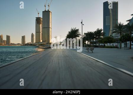 Lusail Corniche at the marina  in Lusail city, Qatar daylight view showing people walking on the promenade  and skyline in background Stock Photo