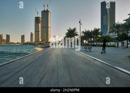 Lusail Corniche at the marina  in Lusail city, Qatar daylight view showing people walking on the promenade  and skyline in background Stock Photo