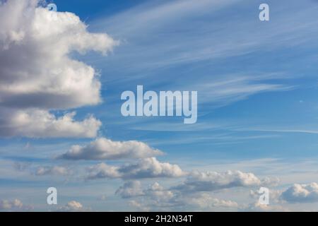 A blue sky background with a texture of white, fluffy clouds floating in a rhythmic row in a semicircle high in the sky. Stock Photo