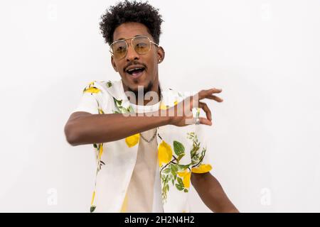 Young Afro-American male in a floral shirt singing and dancing on a white background Stock Photo