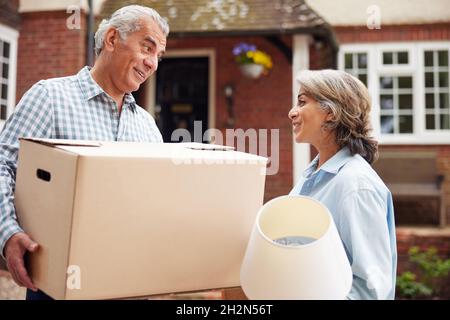 Portrait Of Mature Couple Carrying Boxes On Moving Day In Front Of Dream Home Stock Photo