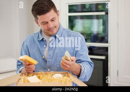 Man Unpacking Online Luxury Cheeses Delivered To Home Stock Photo