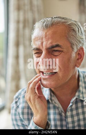 Mature Man At Home Suffering From Pain With Toothache Stock Photo