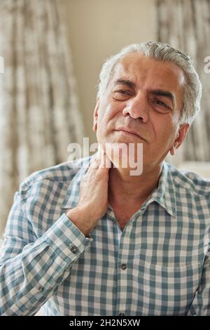 Mature Man At Home Suffering From Muscle Pain Or Ache In Neck Stock Photo