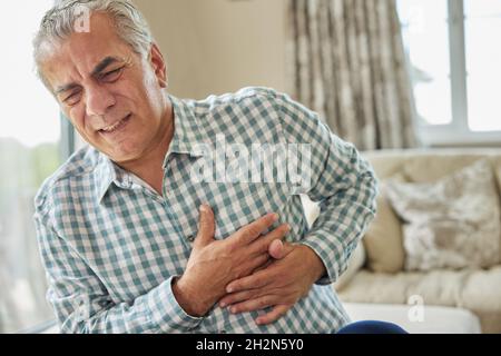 Mature Man Clutching Chest And Suffering Heart Attack At Home Stock Photo