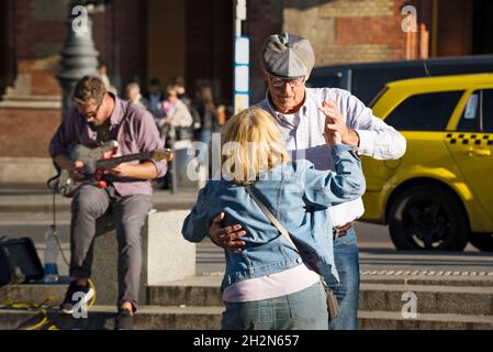 Senior couple dancing in the street while street musician plays electric guitar Stock Photo