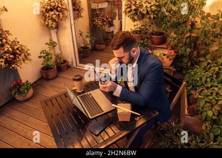 Exhausted businessman holding eyeglasses while working late in office balcony Stock Photo
