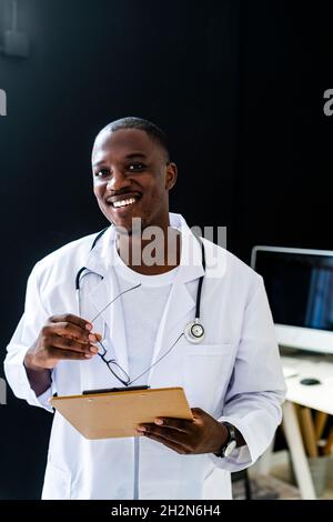 Thoughtful male doctor reading clipboard in medical clinic Stock Photo
