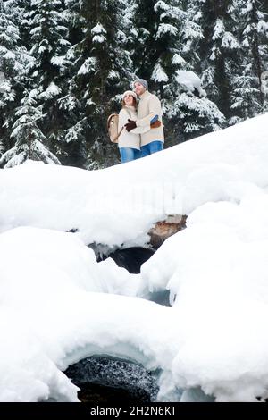 Young couple holding hands while walking on snow Stock Photo