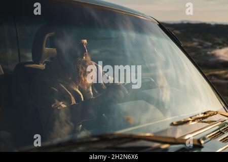 Young man driving car during sunset Stock Photo