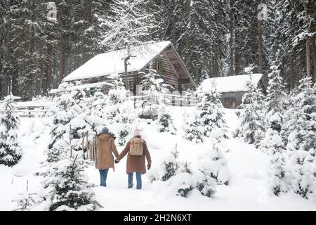 Young couple with sled walking on snow in forest Stock Photo