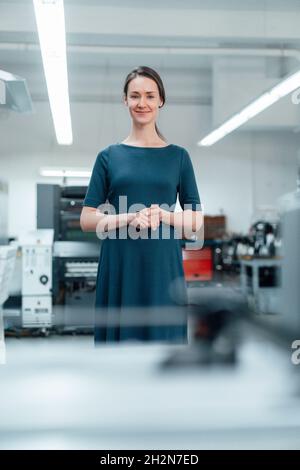 Female professional with hands clasped standing in workshop Stock Photo