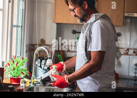 Mature man cleaning glass in kitchen Stock Photo