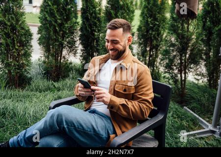 Smiling businessman text messaging through mobile phone at backyard Stock Photo