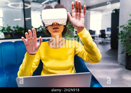 Businesswoman wearing virtual reality headset in office lobby Stock Photo