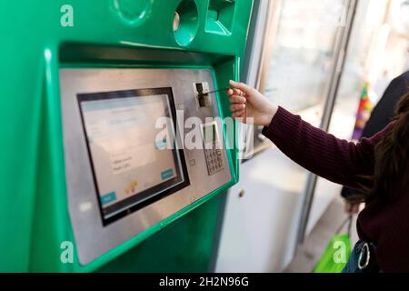 Woman buying ticket from vending machine at tram station Stock Photo
