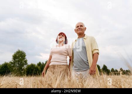 Senior man with hands behind back at wheat field Stock Photo
