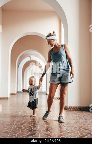 Mother holding hand of son while walking in corridor Stock Photo